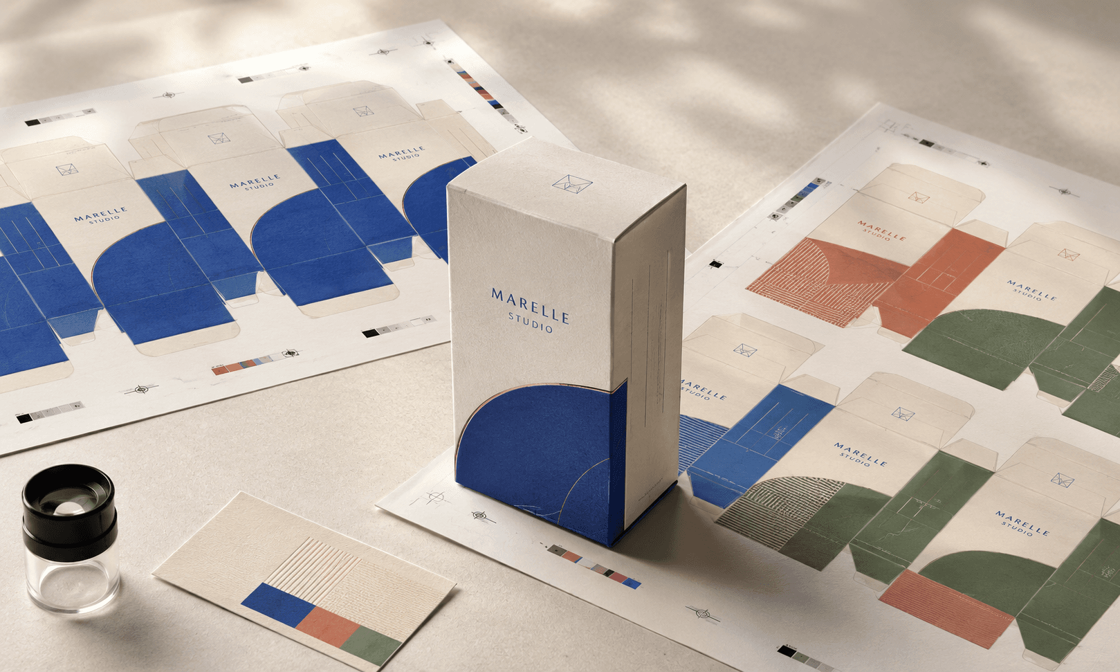 Printed carton proofs showing repeated offset sheets beside varied digital artwork versions in a packaging studio.